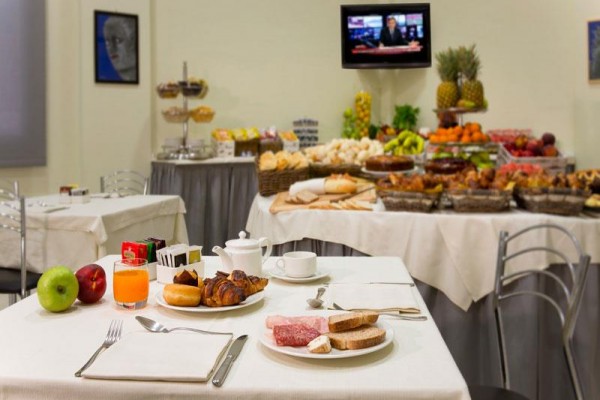 Prostřený stůl s pečivem, ovocem a nápoji v restauraci se švédským stolem.