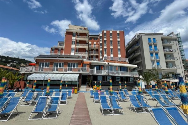 Hotel u pláže se slunečníky a lehátky.
