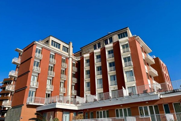 Červená budova s mnoha balkony pod modrou oblohou.  
