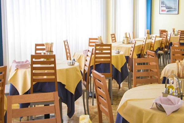 Restaurace se žlutými ubrusy na stolech a dřevěnými židlemi.