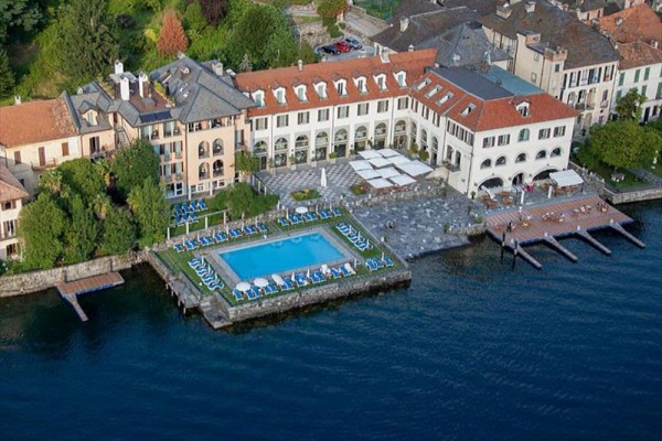 Hotel s bazénem u jezera obklopený zelení.
