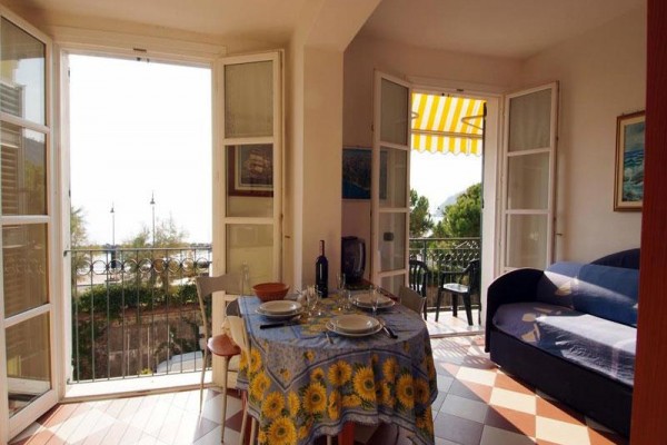 Světlá jídelna s otevřenými francouzskými dveřmi na balkon, ubrus se slunečnicemi na stole.
