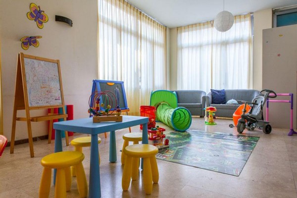 Herna s barevným nábytkem, hračkami a sedačkou.