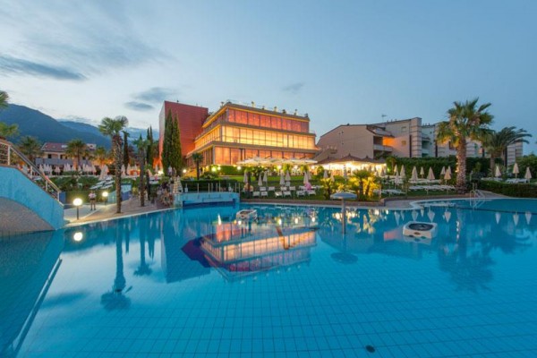 Moderní hotel s osvětlením odrážející se na hladině bazénu za soumraku.