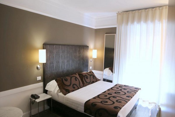 Moderní hotelový pokoj s manželskou postelí a elegantním osvětlením.