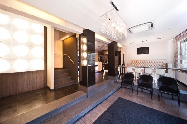 Moderní interiér s designovým osvětlením, schody a černými židlemi.