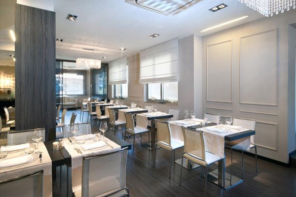 Elegantní moderní restaurace s bílými židlemi a prostřenými stoly.