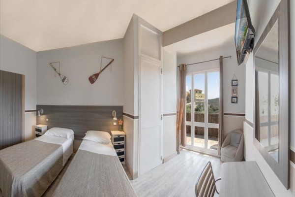 Dva jednolůžkové postele v moderním pokoji s přístupem na balkon a výhledem ven.