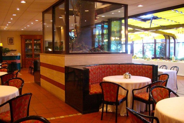 Restaurace s kulatými stoly, židlemi a akváriem uprostřed.