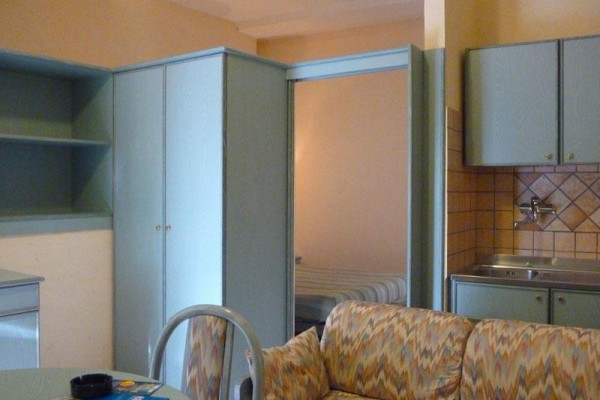 Malý apartmán s kuchyňským koutem, sedací soupravou a skříní.