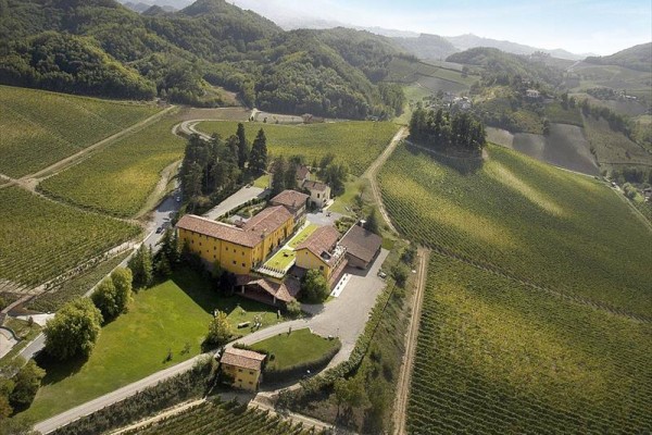 Vinařství obklopené vinicemi a kopcovitou krajinou.