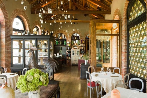 Restaurace s rustikálním interiérem, kamennými oblouky a dřevěným stropem.