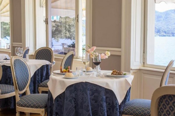 Elegantní restaurace s prostřenými stoly a výhledem na jezero.