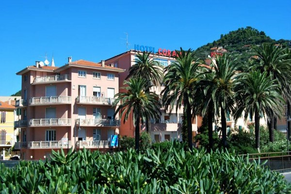 Budova hotelu obklopená palmami s modrou oblohou v pozadí.