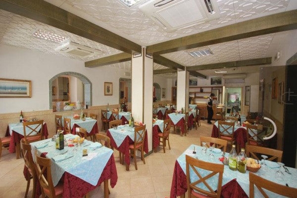 Restaurace s dřevěnými židlemi a stoly pokrytými modrými ubrusy.