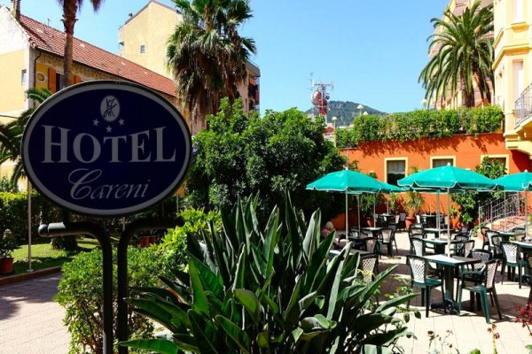 Zahrada s venkovním posezením u hotelu Careni, obklopená palmami a vegetací.