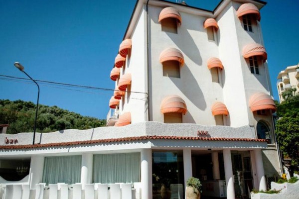 Budova hotelu s oranžovými markýzami na oknech.