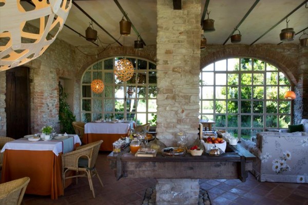 Interiér restaurace s kamennými zdmi, velkými okny a bufetovým stolem s jídlem a nápoji.