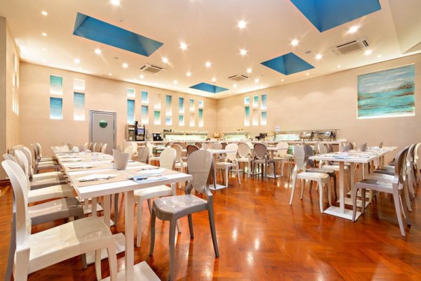 Moderní restaurace s bílými stoly a plastovými židlemi.