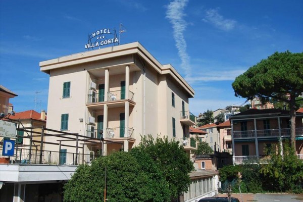 Hotel Villa Costa je čtyřpatrová budova obklopená zelení a jinými stavbami.