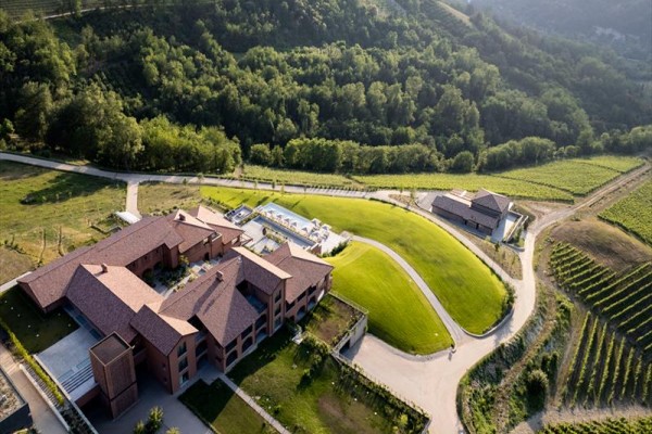 Moderní komplex obklopený zvlněnou krajinou s vinicemi a lesy.