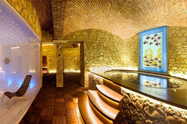 Luxusní wellness prostor s vířivkou a mozaikou na stěně.  