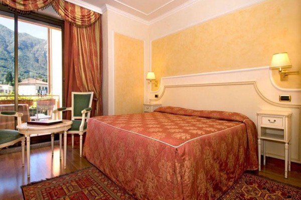 Elegantní hotelový pokoj s dvojlůžkem a balkonem s výhledem na hory.