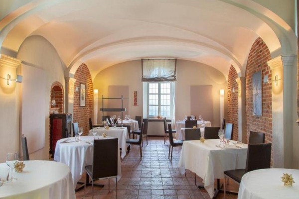 Elegantní jídelna s bílými ubrusy, moderními židlemi a cihlovými stěnami.