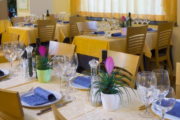 Stoly v restauraci jsou elegantně prostřeny se sklenicemi, talíři a látkovými ubrousky.