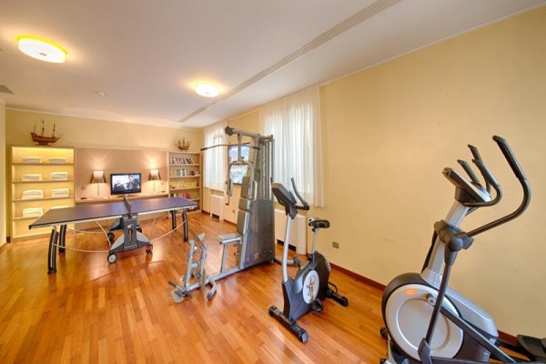 Fitness místnost s posilovacím strojem, rotopedem, pingpongovým stolem a televizí.