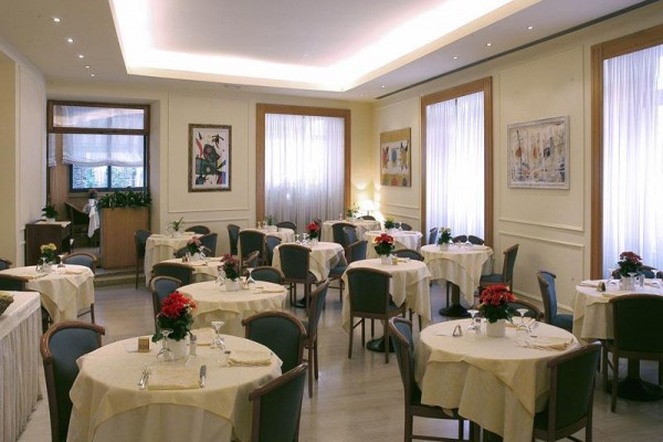 Restaurace s kulatými stoly, židlemi a květinovou výzdobou na stolech.  