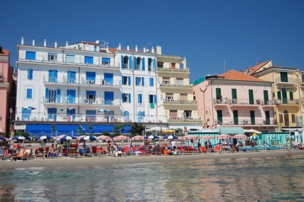 Plážový resort s barevnými budovami a lehátky u moře.