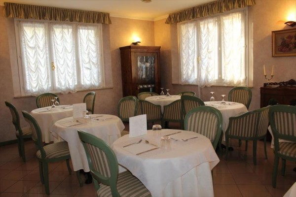 Elegantní restaurace s kulatými stoly a zelenými židlemi.