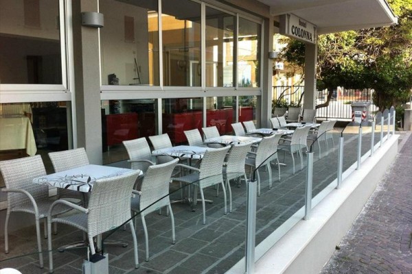 Venkovní terasa restaurace s několika stoly a židlemi.