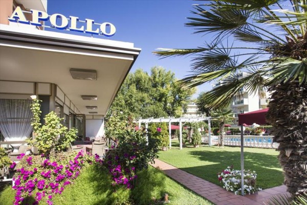 Zahrada hotelu Apollo s palmami a kvetoucími rostlinami.