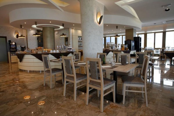 Moderní restaurace s dřevěnými stoly a židlemi na lesklé podlaze.