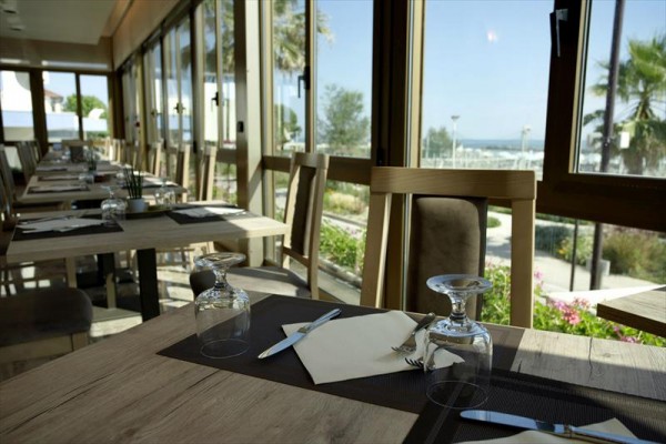 Restaurace s prostřenými stoly a výhledem na zahradu za okny.