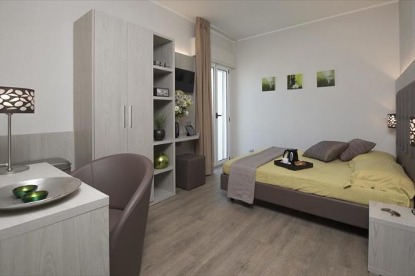 Moderní ložnice s dvojlůžkem, vestavěnými skříněmi a psacím stolem.