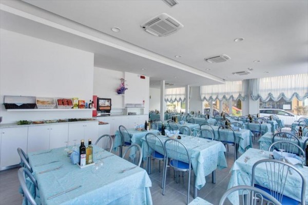 Restaurace s modrými ubrusy a kovovými židlemi u stolů připravených pro hosty.