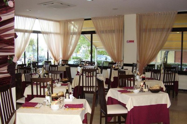 Restaurace s elegantně prostřenými stoly a velkými okny.