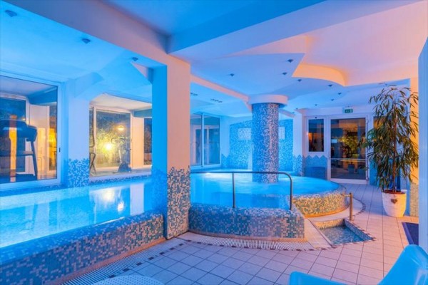 Interiér wellness centra s bazénem osvětlený modrým světlem.
