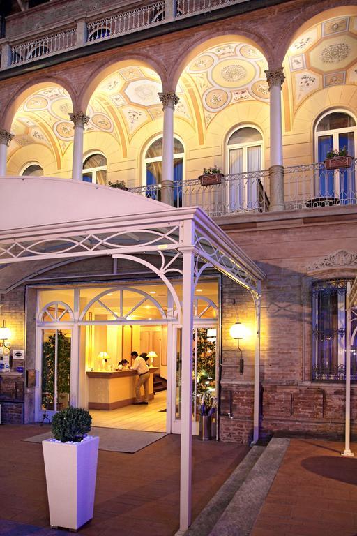 Vstup do hotelu s elegantním osvětlením a arkádovými balkony.