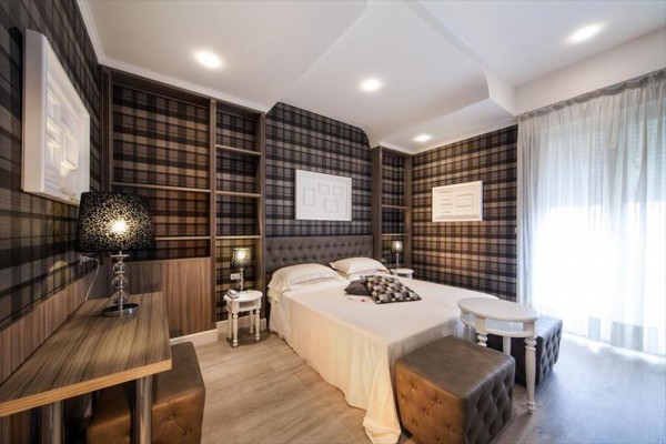 Moderní ložnice s kostkovanými tapetami a světlým dekorem.