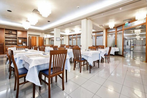 Moderní restaurace s dřevěným nábytkem a bílými ubrusy.