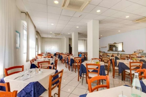 Restaurace s dřevěnými židlemi, bílými ubrusy a modrými běhouny.