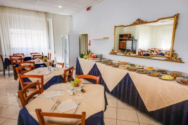 Restaurace s prostřenými stoly a bufetovým stolem plným různých pokrmů.