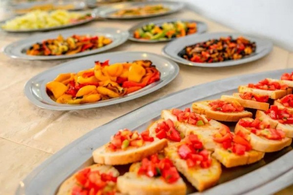 Talíře s různými předkrmy, v popředí bruschetta s rajčaty.  