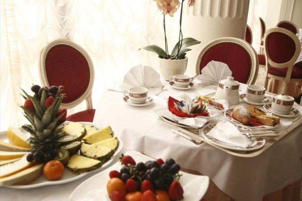 Luxusní jídelní stůl s ovocem, porcelánem a květinou.