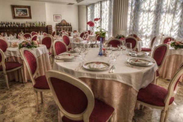 Elegantně prostřený stůl v jídelně s červenými židlemi a květinami uprostřed.