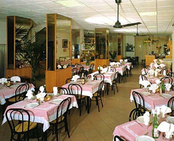 Elegantně prostřená restaurace s růžovými ubrusy a dřevěnými židlemi.